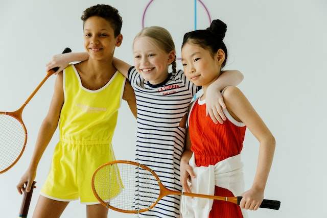 three happy children holding a racket